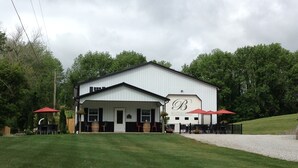 A building with a white exterior, a covered porch, and a sign reading "Brantza Gardens & Winery". - The Bungalow at Brianza Winery (Crittenden)