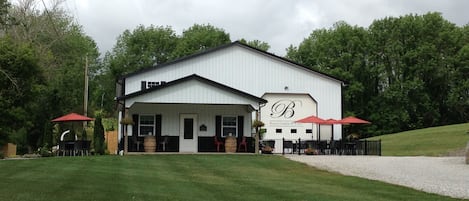 A building with a covered patio area, a garage, and a well-maintained lawn.