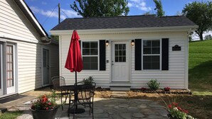 A small white house with black shutters, a red umbrella, and potted plants. - The Bungalow at Brianza Winery (Crittenden)