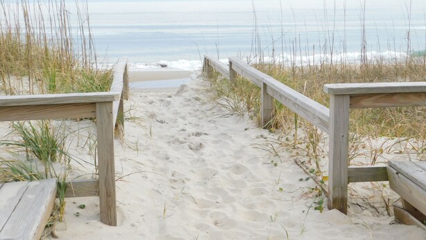 A wooden boardwalk leading to a beach with sand and seaweed. - Beautiful and Spacious, 2 bed 2 full bath, pool and jacuzzi, steps to the ocean (Hatteras)