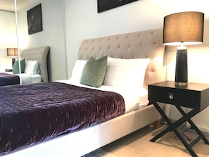 A hotel room with a large bed, a nightstand, and a lamp. - CityLights apartments (Melbourne)