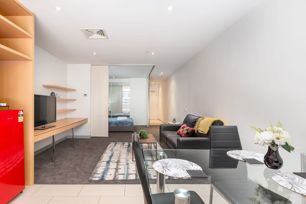 A modern living room with a sofa, coffee table, and a dining area with a glass table and chairs.