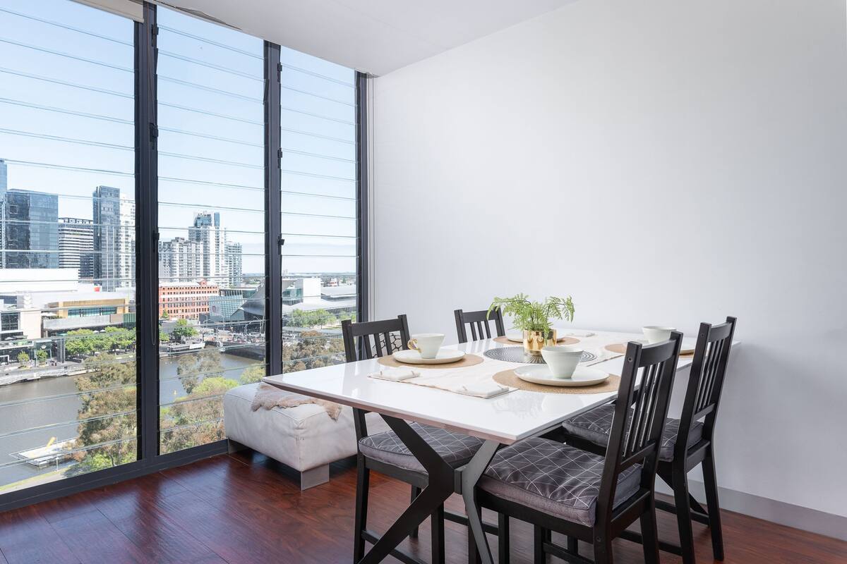 A dining area with a large window overlooking a cityscape and a river.
