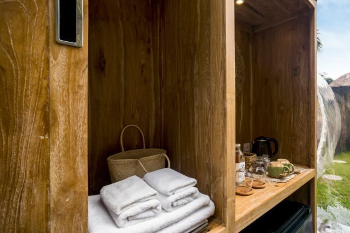 A wooden room with a shelf containing towels, a bag, and a coffee maker.
