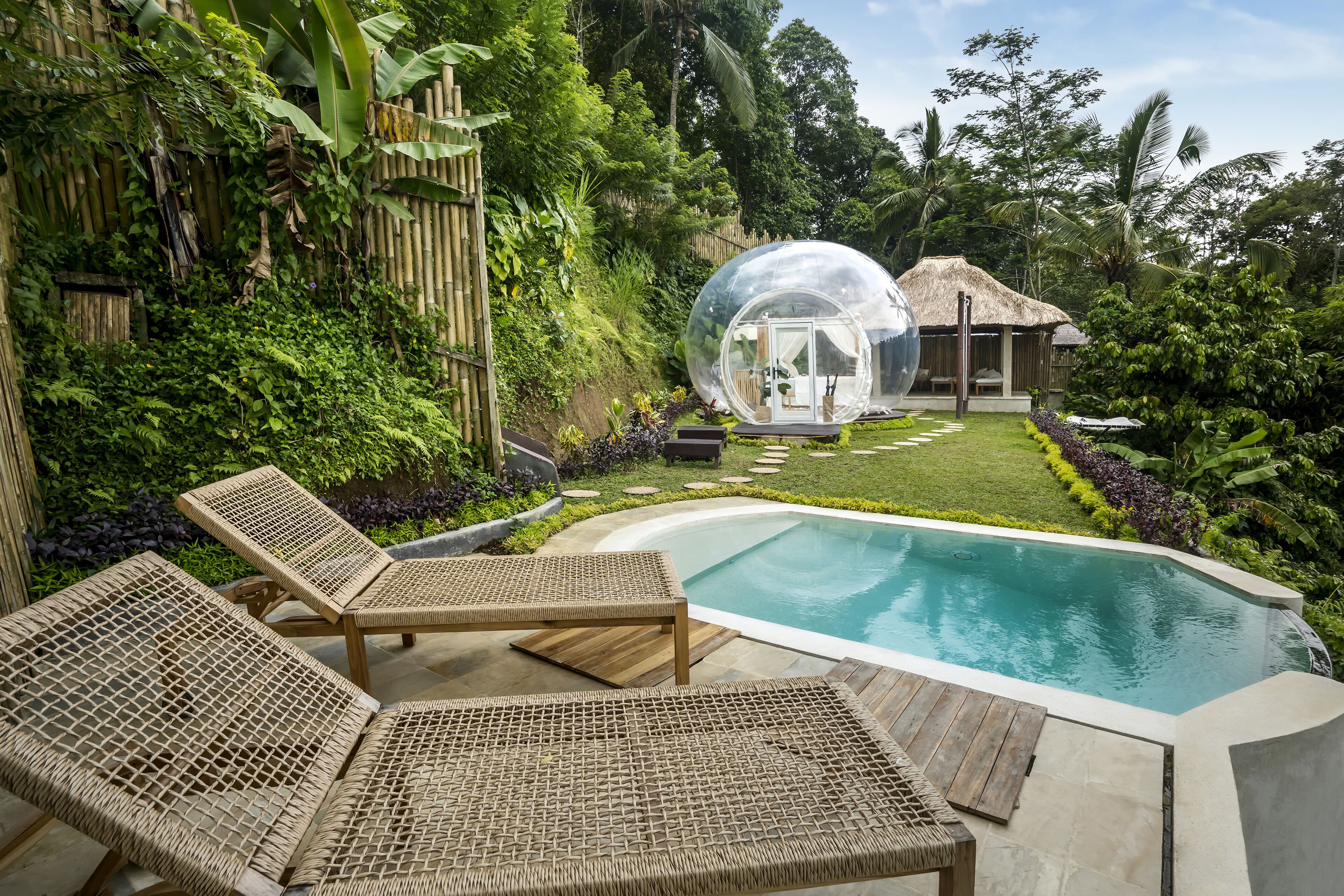Un espace piscine doté de chaises longues, d’un jacuzzi et d’une structure sphérique transparente.