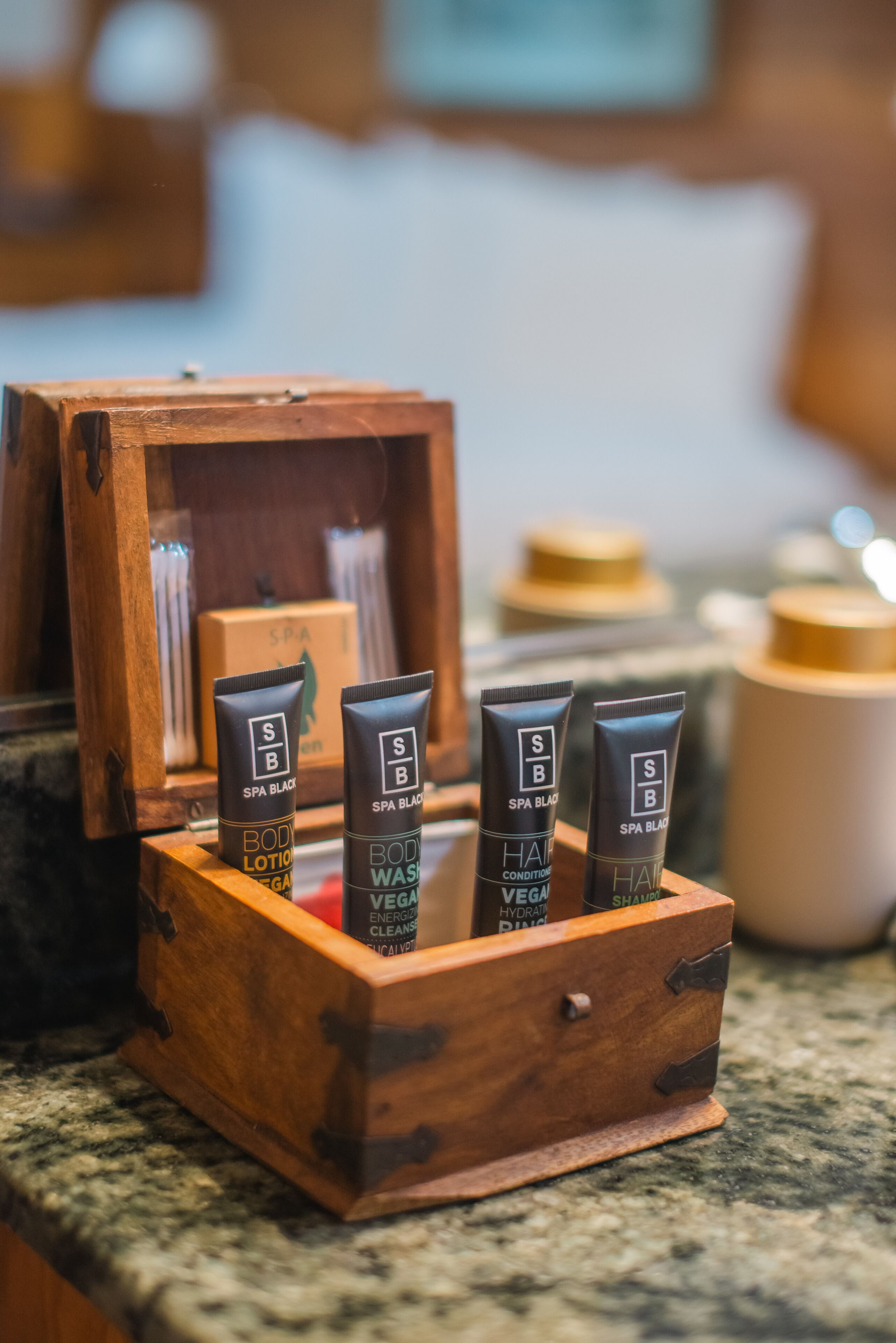 Eine Holzschatulle mit vier Tuben Spa Black Körperlotion und Handseife.
