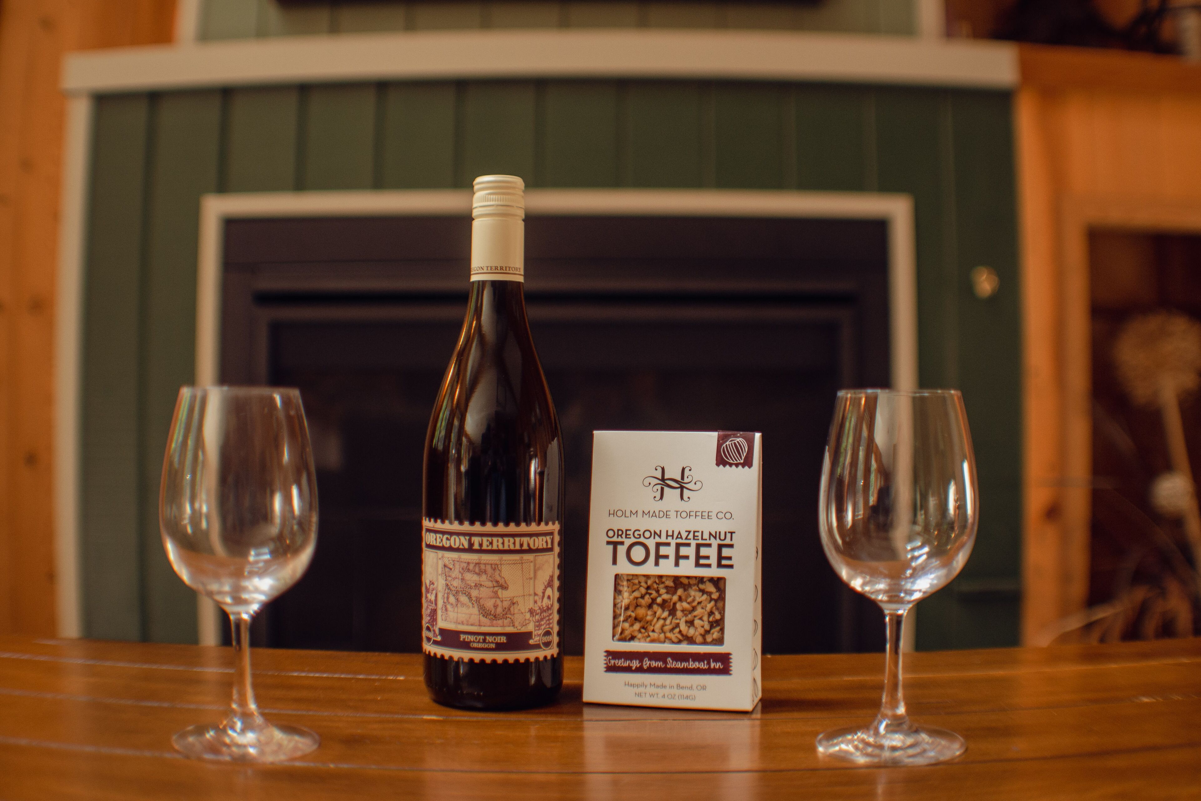 Une bouteille de vin aromatisé aux noisettes de l’Oregon et deux verres à vin vides sur une table en bois.