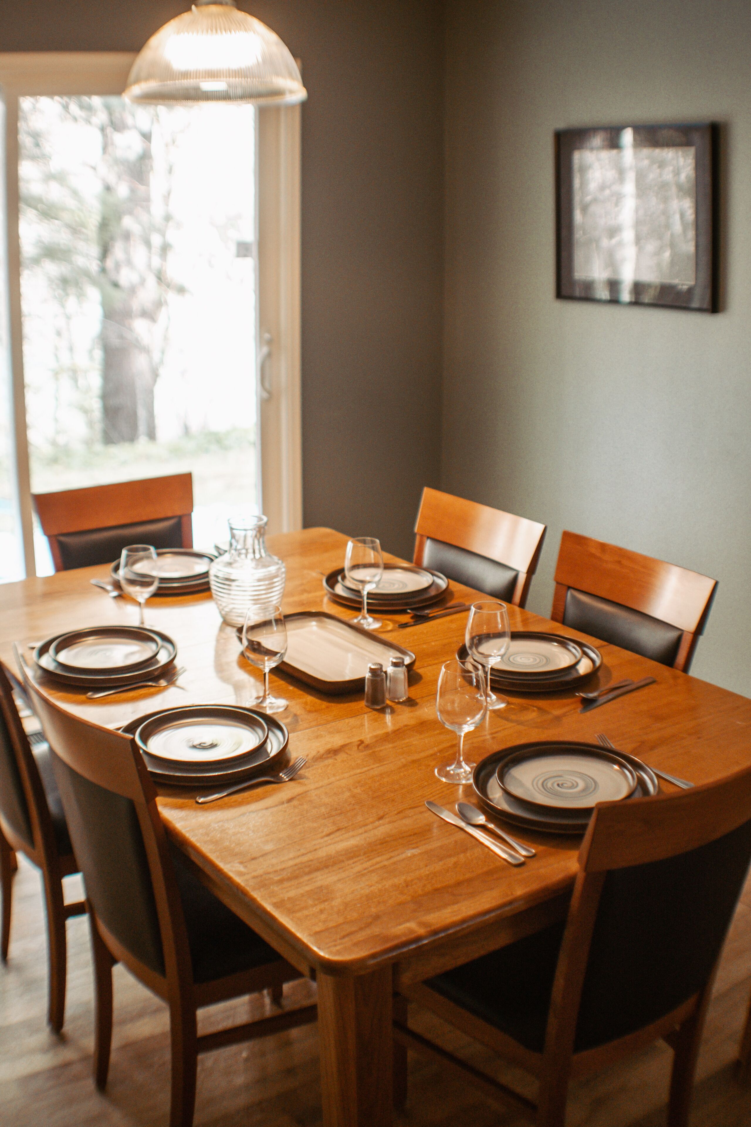 Une table à manger dressée pour six personnes, avec assiettes, verres et couverts.