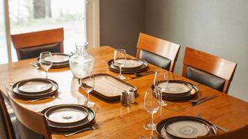 Une table à manger dressée pour six personnes, avec assiettes, verres et couverts.