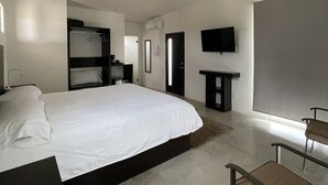 Une chambre d’hôtel moderne équipée d’un grand lit, d’un bureau, d’une chaise, d’un téléviseur à écran plat et d’une armoire.