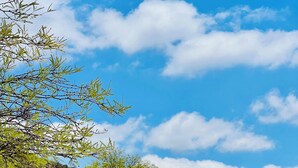 Une voiture ancienne est garée devant un immeuble, avec un ciel bleu dégagé et des montagnes en arrière-plan.