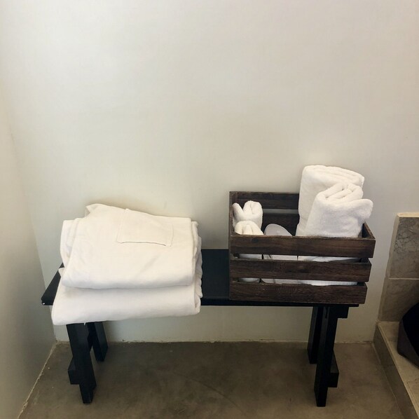 A room with a wooden bench and a small wooden crate containing folded white towels. - Vientos del Valle (Valle de Guadalupe)