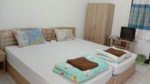 Cama doble con dos almohadas, un armario de madera, un televisor sobre un mueble bajo y una ventana con cortinas.