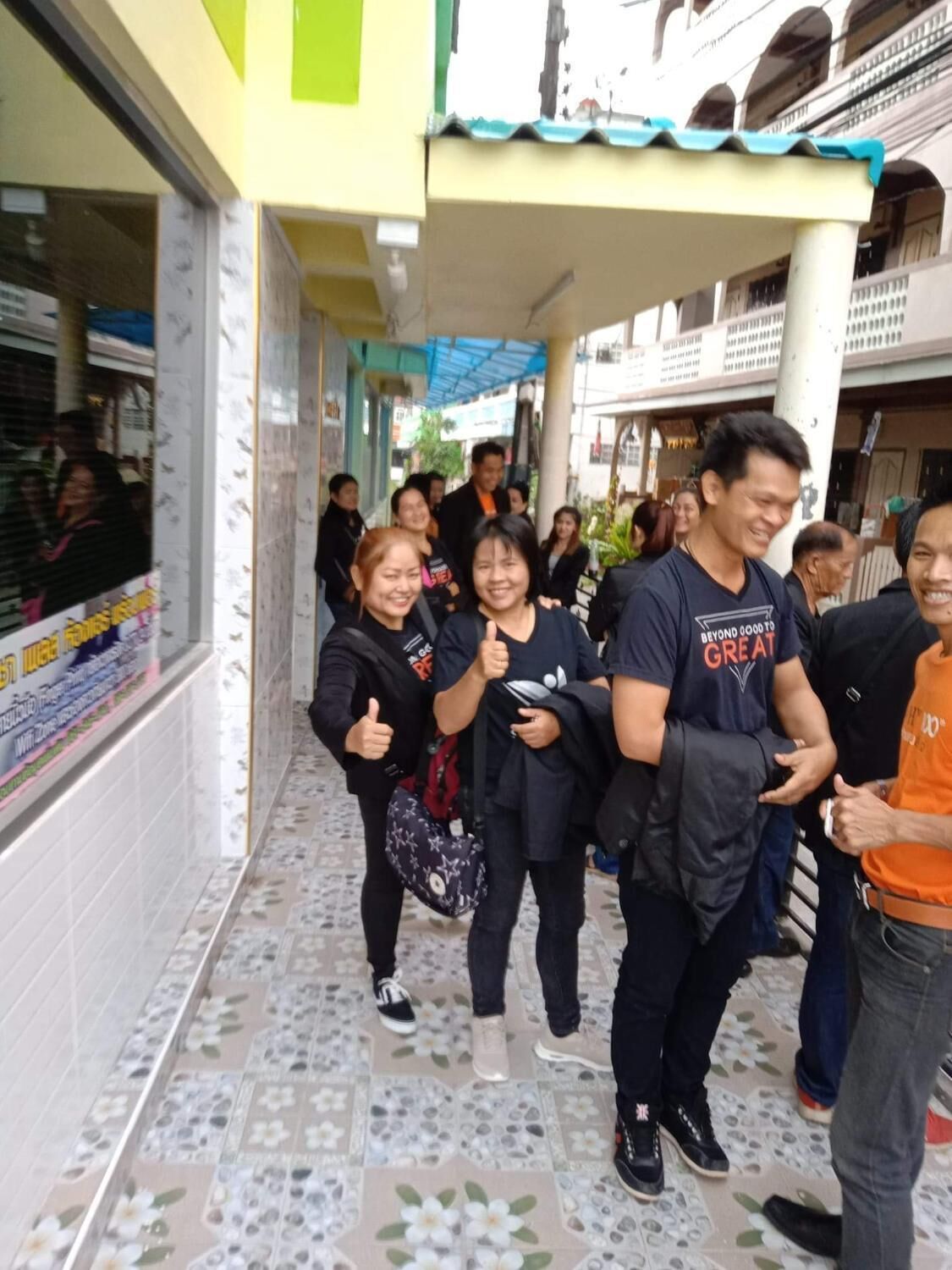 Un grup de persones caminant per un passadís amb terres de rajola i una tenda verda a la part superior.