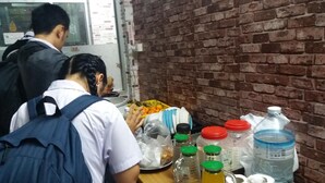 Una mesa con varios objetos, incluyendo botellas, un dispensador de agua y un plato de naranjas.