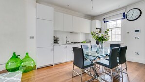 A modern kitchen with white cabinets, a glass dining table, and black chairs.