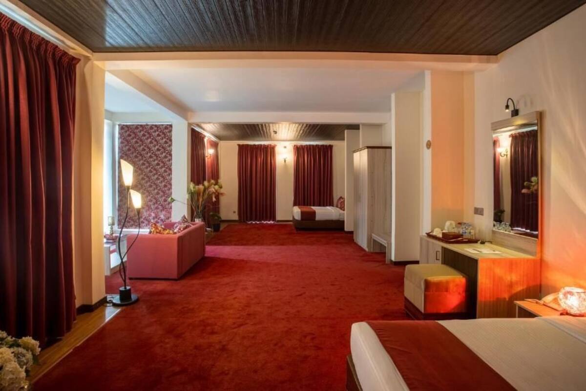 A hotel room with a large bed, a sitting area with a sofa, a desk, and a mirror.