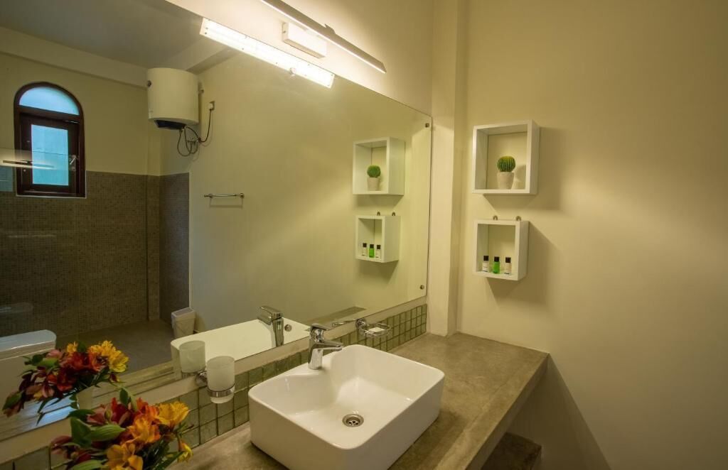 A bathroom with a large mirror, a sink, a toilet, and a window.