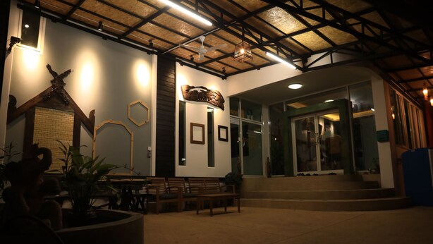 A spacious indoor area with a high ceiling, wooden beams, and a seating area with benches and tables. - Shanmen Art House (Patong)