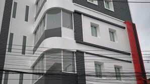 A multi-story building with a modern architectural design, featuring large windows and a prominent red accent on the corner. - Shanmen Art House (Patong)