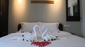 A hotel room with a neatly made bed, two wall-mounted lights, a decorative wooden panel, and a mirror on the wall. - Shanmen Art House (Patong)