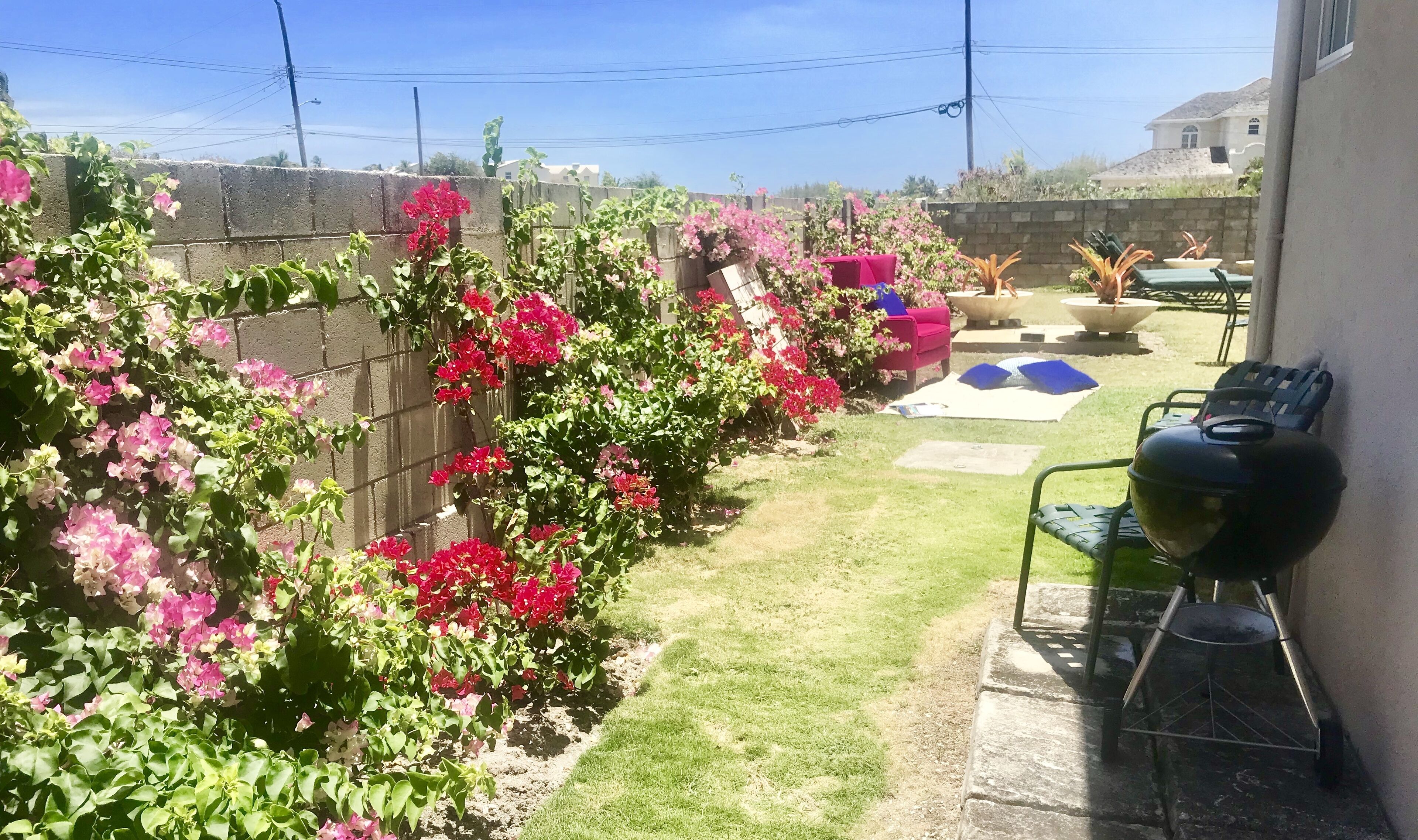 A backyard with a barbecue grill, a red chair, and a table with bowls.