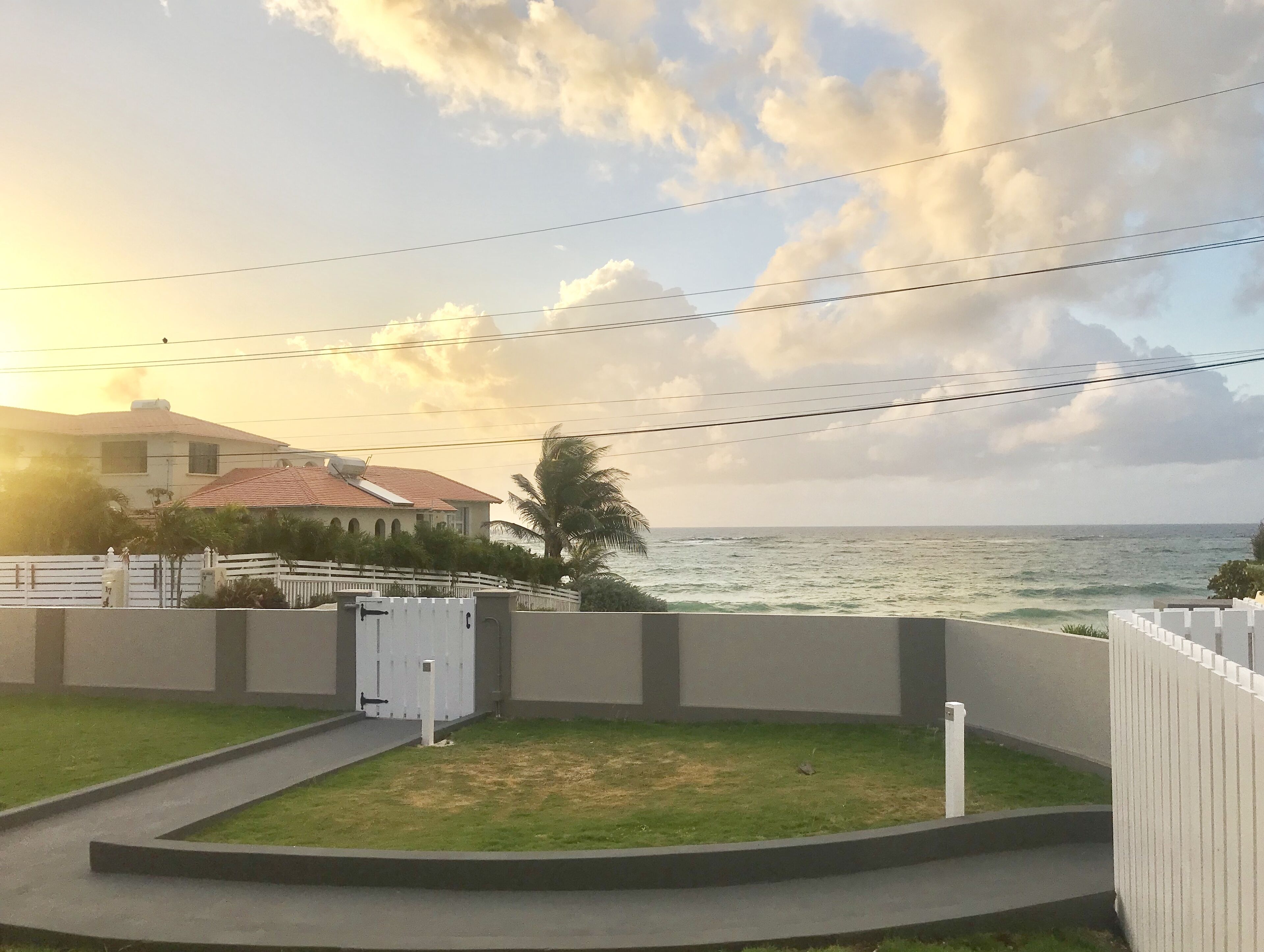 Un quartiere residenziale con una casa, un cortile recintato e vista sull'oceano.