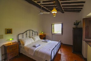 Une chambre à coucher avec un lit, des lampes de chevet, une fenêtre et un ventilateur de plafond.