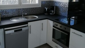 Een moderne keuken met een vaatwasser, oven en een raam boven de gootsteen.