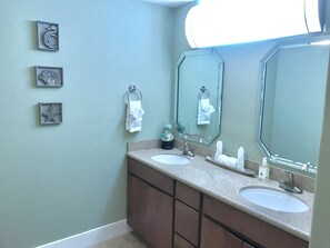 A bathroom with two sinks, a large mirror, and three wall-mounted decorative items. - Waterfront, Dog Friendly, Bring your boat + family beach and dock! (Pensacola Beach)