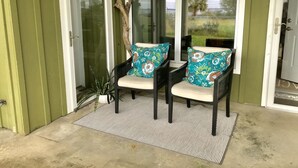 A porch with two chairs, a potted plant, and a view of the outdoors. - Waterfront, Dog Friendly, Bring your boat + family beach and dock! (Pensacola Beach)