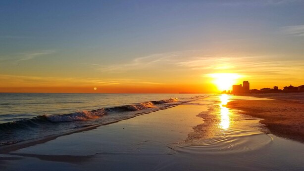 A beach with a sunset, waves, and distant buildings. - Waterfront, Dog Friendly, Bring your boat + family beach and dock! (Pensacola Beach)