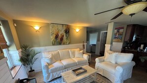 A living room with a white sofa set, a patterned rug, and a ceiling fan. - Waterfront, Dog Friendly, Bring your boat + family beach and dock! (Pensacola Beach)