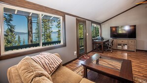 A living room with a large window, a sofa, a coffee table, a TV, and a dining area. - McKinney Cove by Hauserman Rentals (Homewood)