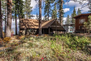 A cabin with a sloped roof, surrounded by tall trees and a natural landscape. - McKinney Cove by Hauserman Rentals (Homewood)