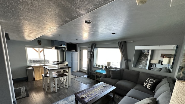 A modern living space with a kitchen, dining area, and a large sofa. - 3 bedrm Luxurious Apartment with Best View in Salt lake City and Private Hot Tub (Draper)