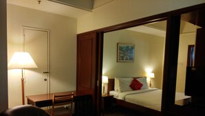 A hotel room with a bed, bedside lamps, a desk with a chair, a lamp, and a painting on the wall. - Time Square By Trivaa (Kuala Lumpur)