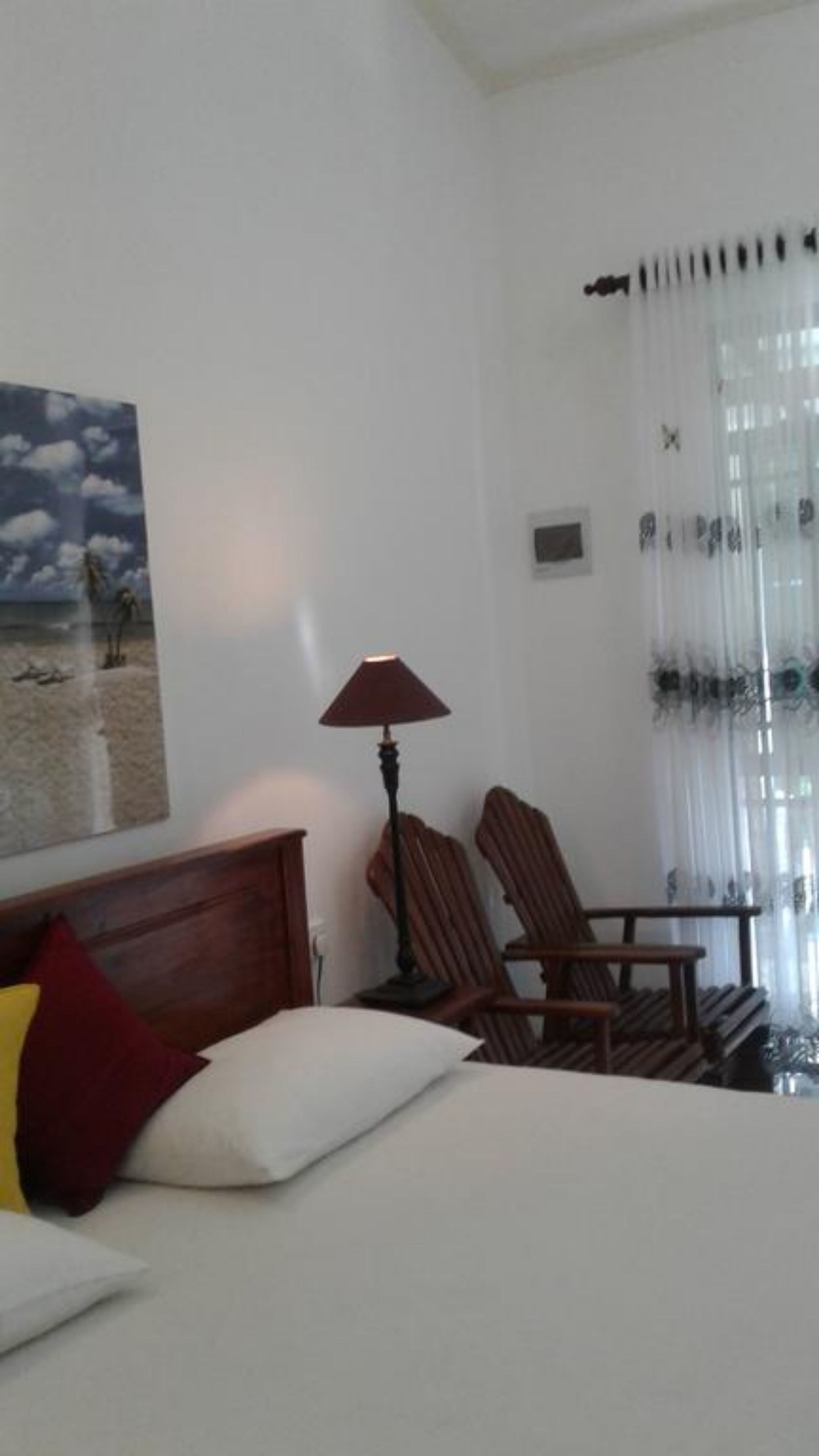 Habitación de hotel con cama, escritorio, silla, lámpara, un cuadro y ventana con cortinas.
