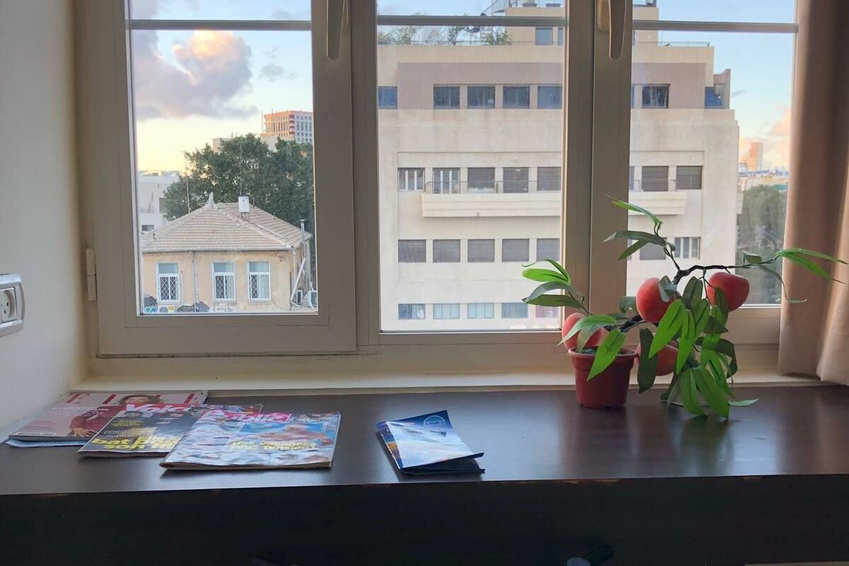 A room with a desk, chair, and a window with a view of buildings.