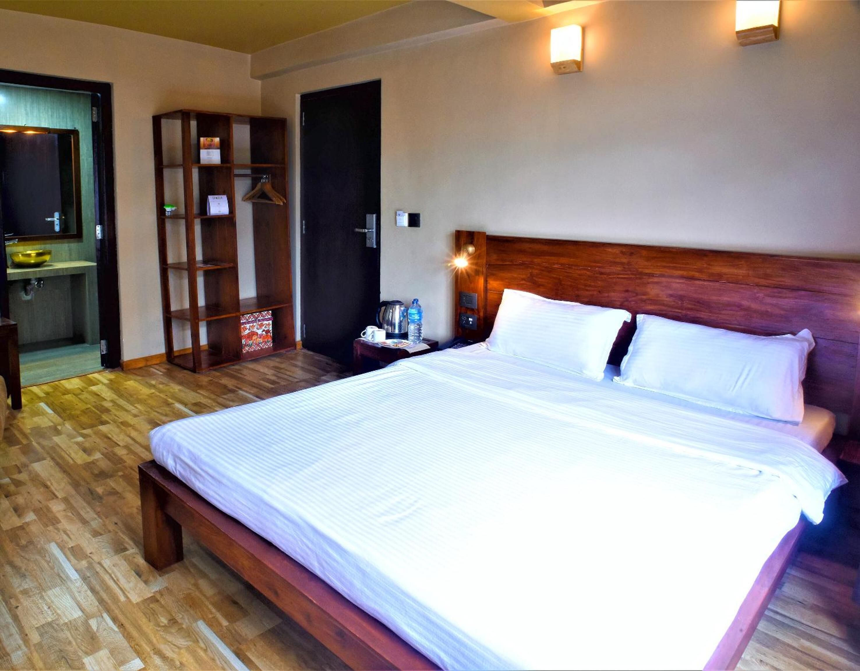 A hotel room with a large bed, wooden headboard, bedside table, and a wardrobe.