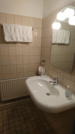 A bathroom with a white sink, a mirror with lights, and a towel rack. - H&S Hotel Wildpferd (Duelmen)