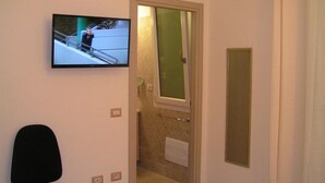Un baño con ducha, inodoro y televisor montado en la pared.