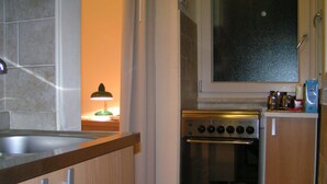 Una cocina con estufa, armarios, ventana y lámpara.