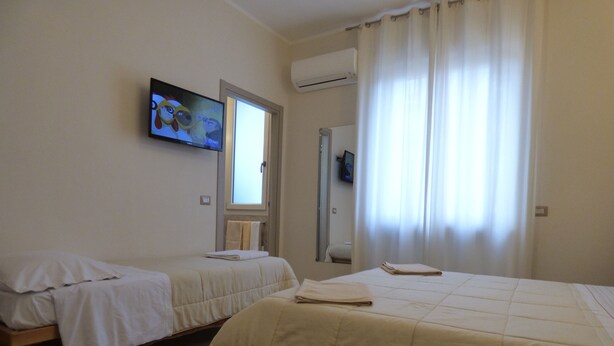 Una habitación de hotel con dos camas, un televisor en la pared y una ventana con cortinas.