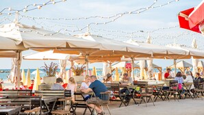 An outdoor seating area with tables and chairs under umbrellas, overlooking the beach. - Premium suites on Beach Ben Yehuda 43 (Tel Aviv)