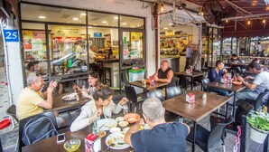 An outdoor dining area with tables and chairs, a Coca-Cola refrigerator, and a visible storefront with glass windows. - Premium suites on Beach Ben Yehuda 43 (Tel Aviv)