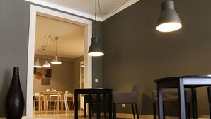 Un comedor con una mesa y sillas, un florero y luminarias colgantes.