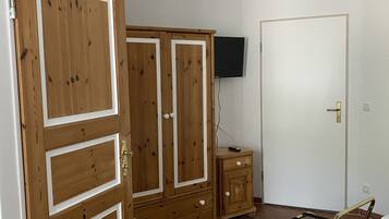 Ein Schlafzimmer mit Holzschrank, Nachttisch, Bett und Wandfernseher.