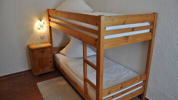 Una cama litera de madera con una mesita de noche y una lámpara.