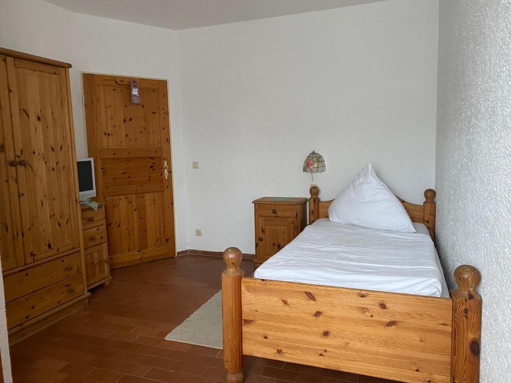 Un dormitorio con una cama de madera, un armario de madera y una mesita de noche.